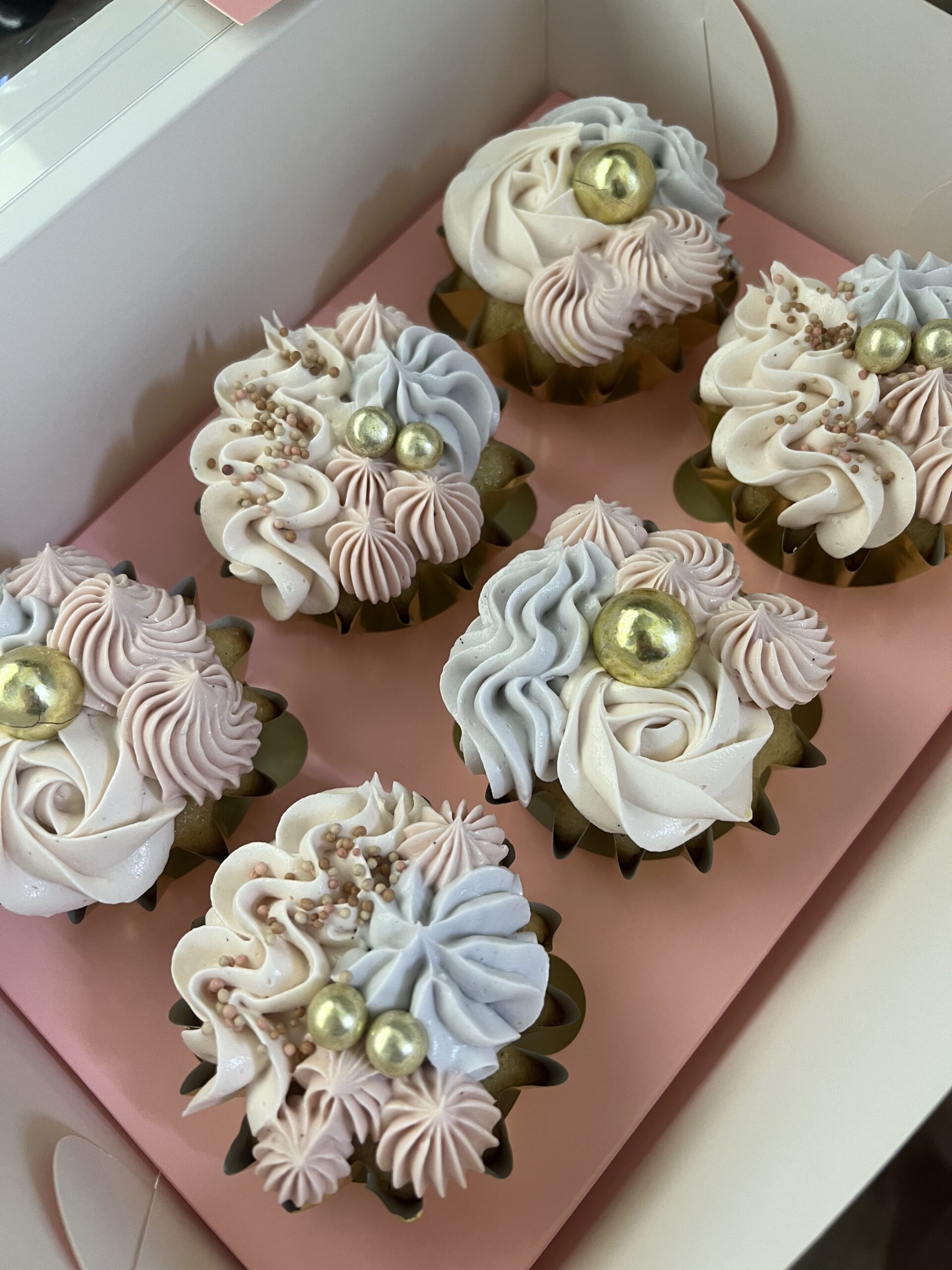 Custom pastel buttercream cupcakes with pink and blue swirled piping and gold accents, perfect for birthdays and special events in Ayr.