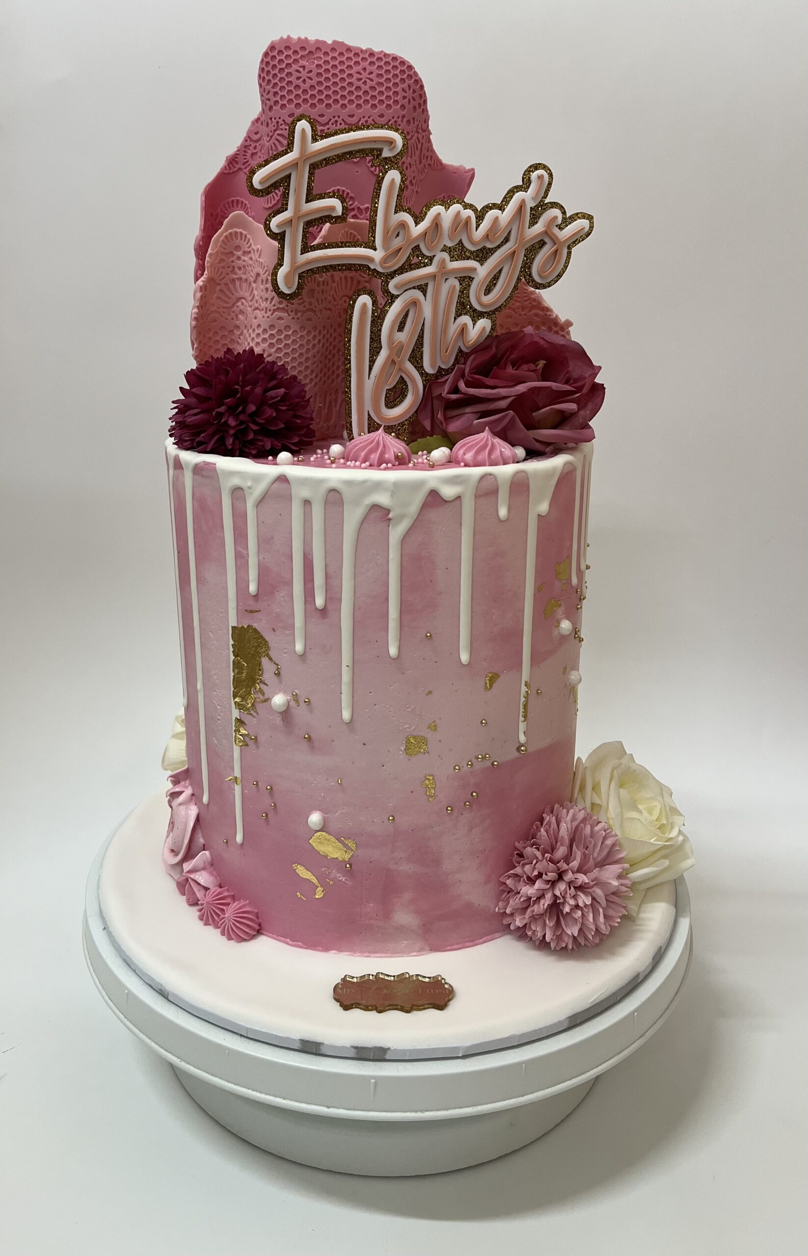 Custom pink drip cake with gold leaf accents and floral detailing, perfect for birthdays and special celebrations in Ayr.