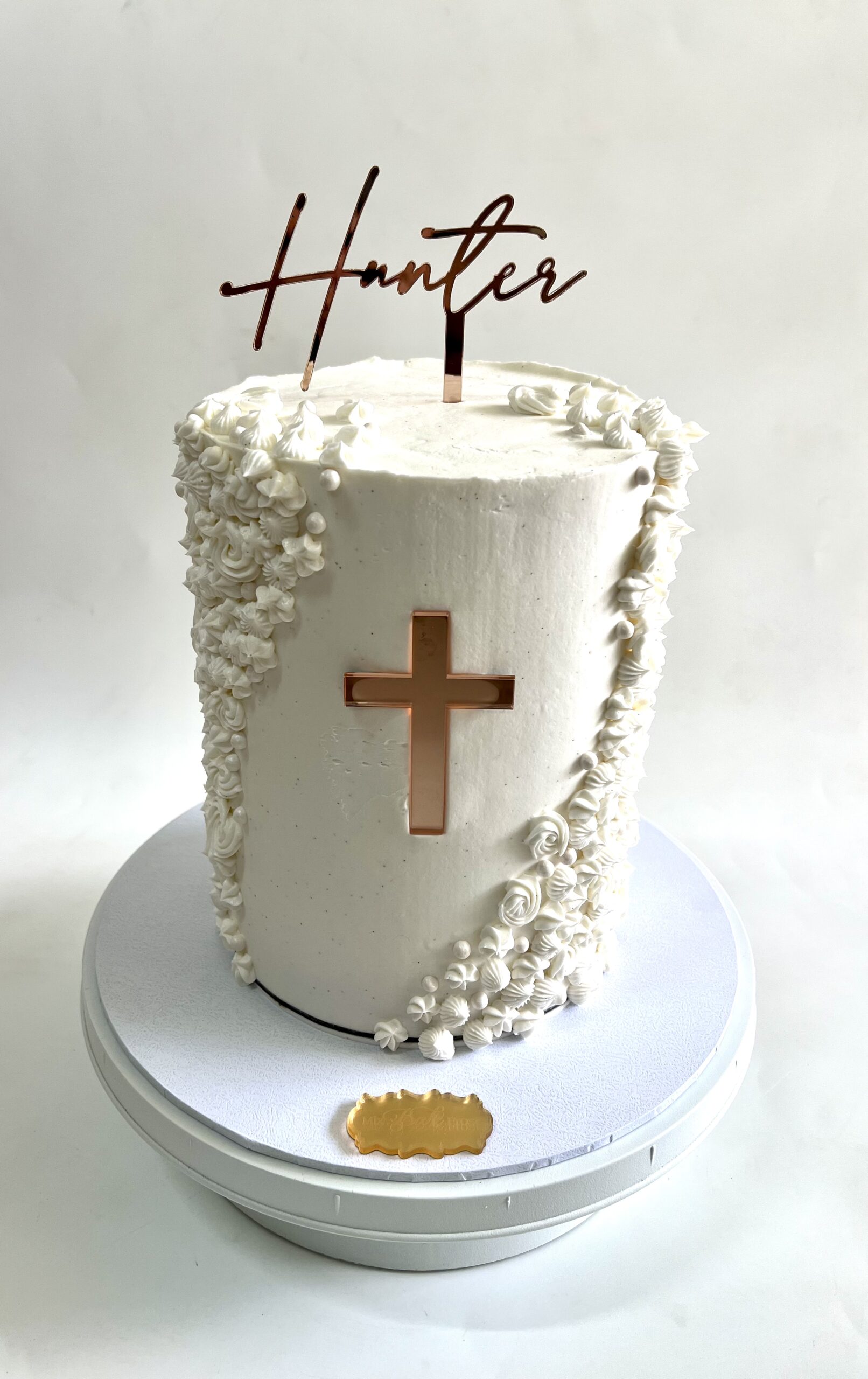 Custom white buttercream baptism cake with textured floral piping and gold cross detail, handcrafted for special celebrations in Ayr.
