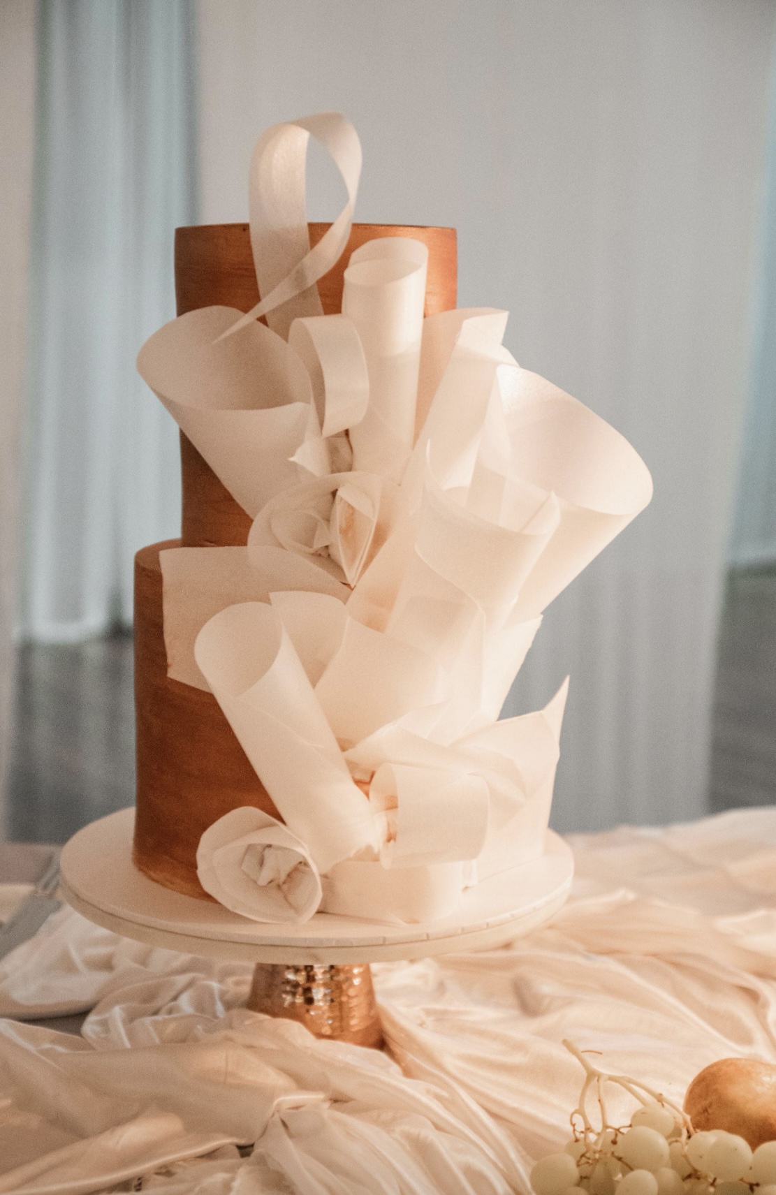 Contemporary white celebration cake with sculptural fondant detailing and soft neutral tones, handcrafted for special occasions.