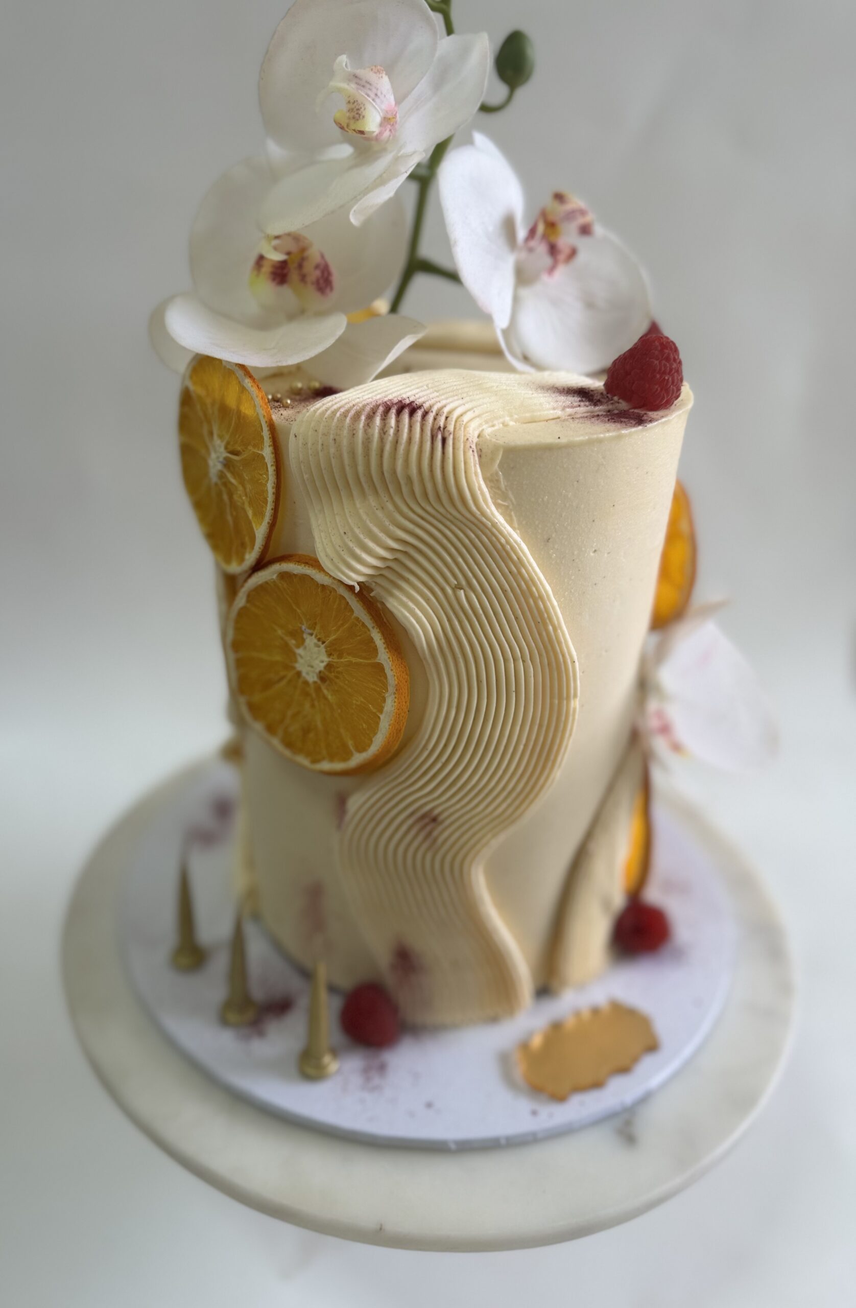 Buttercream celebration cake with textured finish, dried citrus slices and fresh florals, custom made in Ayr.